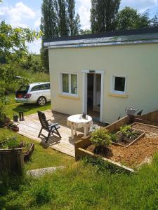 Casa blanca pequeña con mesa y patio en La petite maison au calme dans les champs, en Matton-et-Clémency