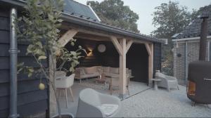 een tuinhuisje met een bank en stoelen op een patio bij Monumentale stolpboerderij voorzien van alle gemakken van nu! in Twisk