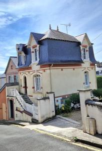a large white house with a blue roof at Bel appartement, 2 chambres, Parking, proximité plage et centre ville in Trouville-sur-Mer