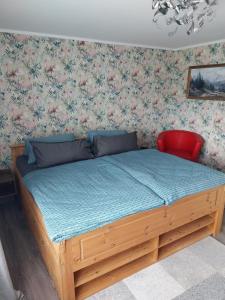 ein Holzbett in einem Schlafzimmer mit Blumentapete in der Unterkunft Einliegerwohnung in Gissigheim. in Königheim