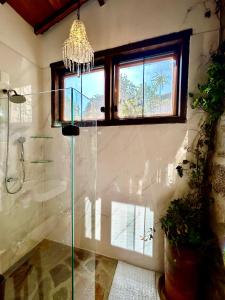 uma casa de banho com um chuveiro em vidro e um lustre. em Segredo da Serra Guest House em Tiradentes