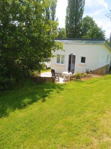 una casa blanca con un banco en un patio en La petite maison au calme dans les champs, en Matton-et-Clémency