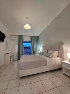 a bedroom with a large white bed and a television at Maria Studios in Paleokastritsa