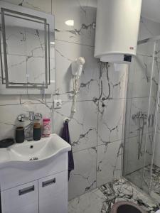 ein weißes Badezimmer mit Waschbecken und Dusche in der Unterkunft MM apartman in Mladenovac + 13 Fotos