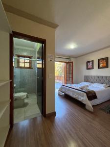 a bedroom with a bed and a glass shower at Pousada Aconchego na Montanha in Campos do Jordão