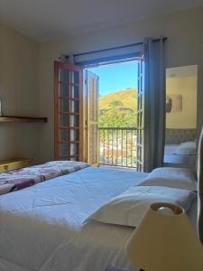 sypialnia z 3 łóżkami i dużym oknem w obiekcie Pousada Aconchego na Montanha w mieście Campos do Jordão