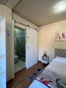 a bedroom with a bed and a bathroom with a shower at Pousada Aconchego na Montanha in Campos do Jordão