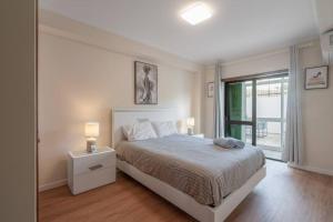 a white bedroom with a bed and a window at Terrace Beach Apartment in Buarcos