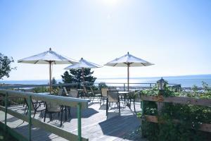 una terraza con mesas y sillas y sombrillas en Hotel La Roche Pleureuse, en L'Isle-aux-Coudres
