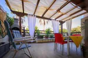 a patio with chairs and a table with a pergola at Residenza Grecale, con veranda, in zona residenziale tranquilla, a due passi dal paese in Stintino