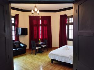 a bedroom with red curtains and a bed and a table at GREEN ORCHID HOSTEL Miraflores Lima in Lima