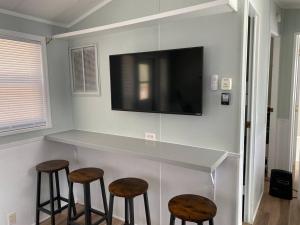 a kitchen with two stools and a counter with a tv at Tiny House at Piney point in Piney Point