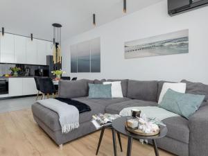 a living room with a gray couch and a table at Beautiful apartment overlooking the river, swimming pool, sauna, Dziwnów in Dziwnów