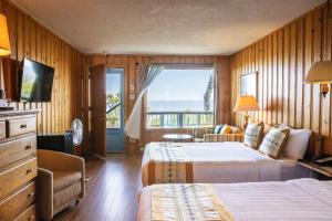 a hotel room with two beds and a balcony at Hotel La Roche Pleureuse in L'Isle-aux-Coudres