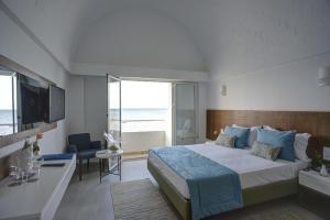 a bedroom with a bed and a desk and a window at Monarque Dar Jerba Narjess in Taguermess