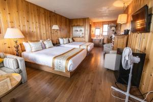 Habitación con 2 camas, paredes de madera y suelo de madera. en Hotel La Roche Pleureuse, en L'Isle-aux-Coudres