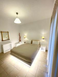 ein Schlafzimmer mit einem Bett mit zwei weißen Tischen in der Unterkunft Anemonisia Deluxe Apartments in Skyros