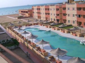 Blick auf ein Resort mit einem Pool mit Sonnenschirmen in der Unterkunft شاليه سياحي مكيف صف أول علي البحر مباشره ومكيف وبحديقه خاصه in Ras Sudr