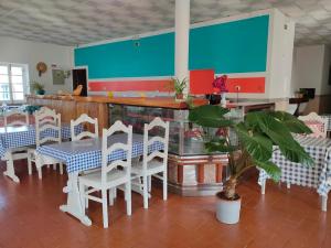 un restaurante con sillas blancas y una mesa con una planta en Vicentina Rooms by Casas do Alentejo, en Almograve