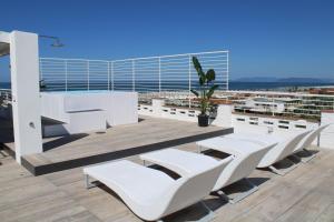 Hotel Esplanade في مارينا دي بيتراسانتا: مجموعة من الكراسي البيضاء والطاولات على الشرفة