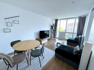een woonkamer met een tafel, stoelen en een bank bij l'écrin de la mairie in Colombes