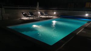 uma piscina à noite com cadeiras e uma mesa em Apartmani Naomi&Leo em Senj