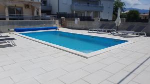 a swimming pool with two chairs next to a house at Apartmani Naomi&Leo in Senj