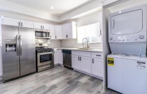 una cocina con armarios blancos y electrodomésticos de acero inoxidable en Ktown Homestay en Los Ángeles