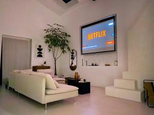 sala de estar con sofá y TV en la pared en Maison d'exception Girondine en La Lande-de-Fronsac