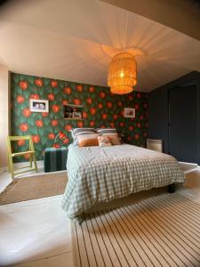 a bedroom with a bed with a green wall with tomatoes at la petite maison Normandie in Saint-Cyr-du-Bailleul