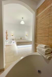 a bathroom with a bath tub and a bedroom at Anemonisia Deluxe Apartments in Skiros
