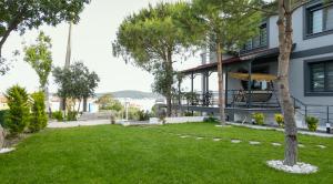 a view of the front of a building with a yard at Select Cunda Guest House - Sea View Room with Private Veranda in Cunda Island in Ayvalık