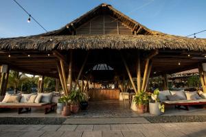 einem großen strohgedeckten Pavillon mit Sofas und Pflanzen in der Unterkunft Blue Venao CONDO APARTMENT C32 in Playa Venao