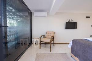 ein Schlafzimmer mit einem Stuhl und einem Fernseher an der Wand in der Unterkunft Select Cunda Guest House - Sea View Room with Private Veranda in Cunda Island in Ayvalık