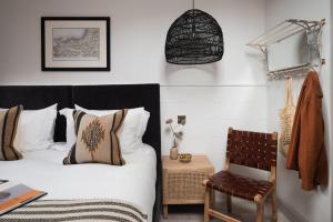 a bedroom with a bed and a chair at Kittiwake apartment - Coastal, luxury, self-catering in Port Isaac