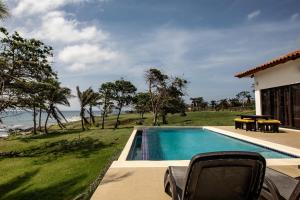 einen Pool mit Stühlen und Meerblick in der Unterkunft Super Private Beachfront 3BR Villa with Infinity Pool Andromeda Pedasi in Pedasí Town