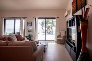 ein Wohnzimmer mit einem Sofa und einem TV in der Unterkunft Super Private Beachfront 3BR Villa with Infinity Pool Andromeda Pedasi in Pedasí Town