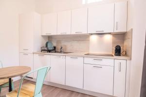 アンティーブにあるStudio Vieil Antibes Proche Merの白いキャビネット、テーブルと椅子付きのキッチンが備わります。
