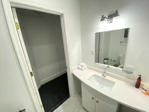 La salle de bains blanche est pourvue d'un lavabo et d'un miroir. dans l'établissement Gorgeous Refurbished 1Bdrm and 1Den Home, à Washington