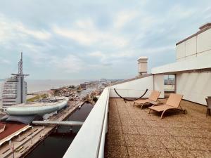 balcone con sedie e vista sulla città di COAST HOUSE Sky Suite a Bremerhaven
