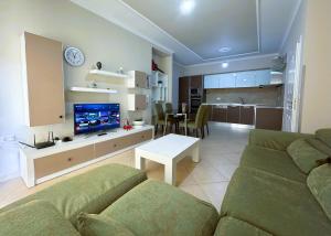 a living room with a couch and a tv and a table at H-Apartment Lungo Mare in Vlorë