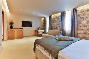 a bedroom with a bed and a chair and a television at Boutique hotel Ruzmarin SPA & Garden by Aycon in Budva