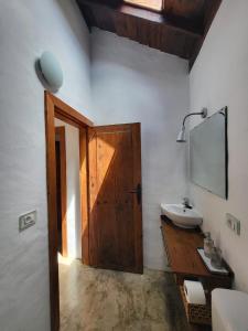 a bathroom with a sink and a wooden door at Auténtica Casa Rústica Canaria in Puntagorda