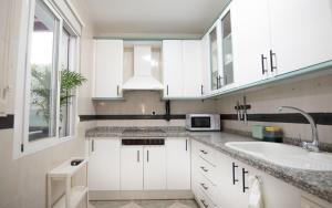 a white kitchen with a sink and a microwave at Mar y montaña in Monachil