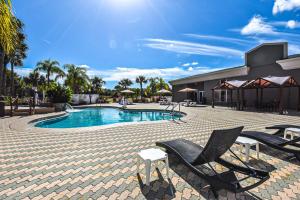 a swimming pool with two chairs and a building at Holiday Inn Express & Suites Cocoa by IHG in Cocoa