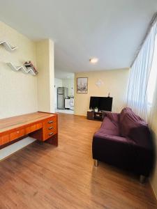 uma sala de estar com um sofá e uma televisão em Departamento en Condominio Comas em Lima