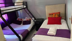 two beds in a room with purple and white at Happy Holiday Backpackers in Victoria Falls