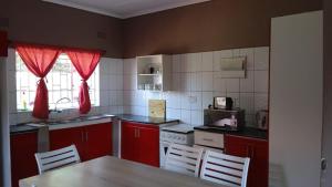 uma cozinha com armários vermelhos, uma mesa e cadeiras em Happy Holiday Backpackers em Victoria Falls