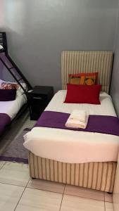 um quarto com uma cama grande e uma almofada vermelha em Happy Holiday Backpackers em Victoria Falls