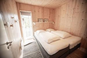 a bed in a wooden room with a window at Luxury cottage - in amazing surroundings in Sandur